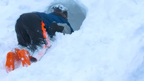 Young Boy Digging a Hole into the Side of a Snowbank Stock Footage 102929349