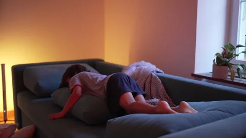 Young boy diving barefoot into a couch, letting his body fall onto cushions.. Stock Footage 287621932