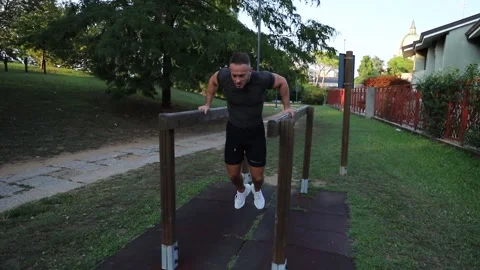 Young boy does parallel bars dips outdoor in the park. Stock Footage 149746586