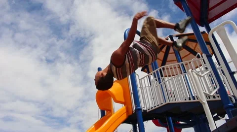 Young boy doing backflip off bar at playground Vídeos de archivo 53769824