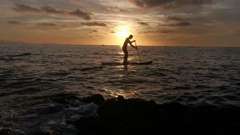 Young boy doing paddle surf at sunset Stock Footage 135744489