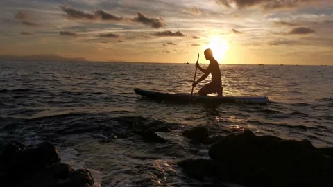 Young boy doing paddle surf at sunset Stock Footage 135744590