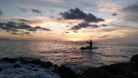 Young boy doing paddle surf at sunset Stock Footage 135744866