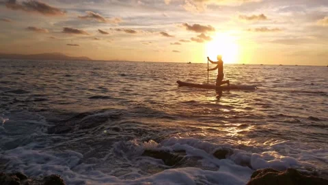 Young boy doing paddle surf at sunset Stock Footage 135745491