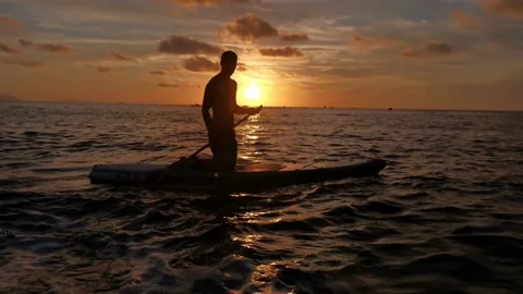 Young boy doing paddle surf at sunset Stock Footage 135745631