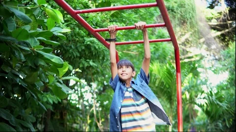 Young boy doing pull ups on monkey bars in park Stock Footage 312690894