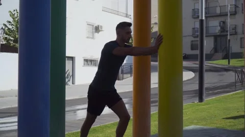 A young boy doing stretching exercises between coloured columns Stock Footage 250935380