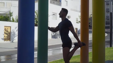 A young boy doing stretching exercises between coloured columns Stock Footage 250935401