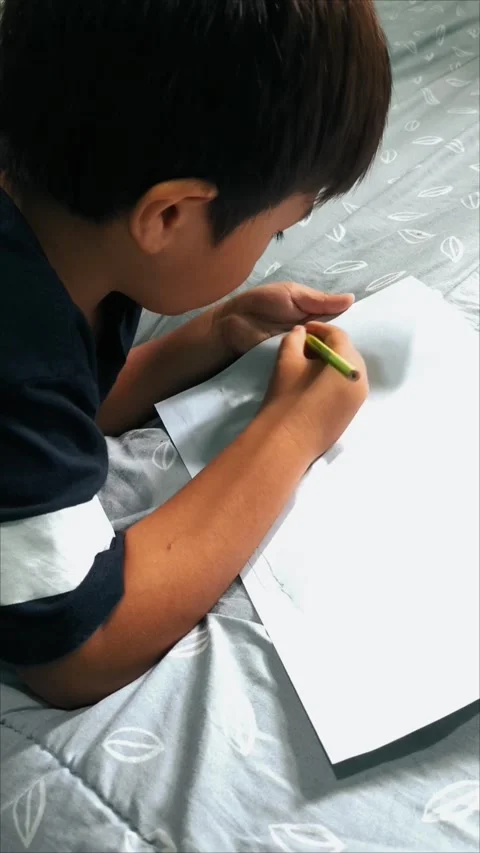 Young Boy Drawing or Writing on a Bed Stock Footage 312104531