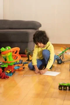Young boy drawing on paper next to dinosaur toys Fotos Stock