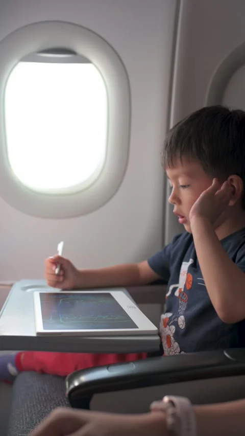 Young boy drawing on tablet during flight Stockbeeldmateriaal 337788400