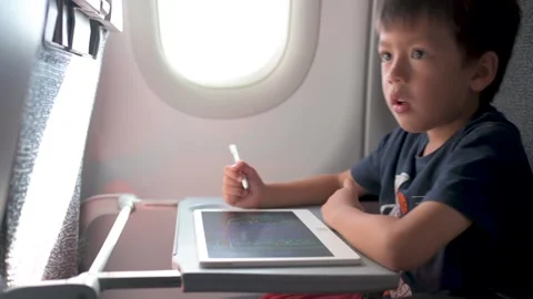 Young boy drawing on tablet while flying in an airplane 動画素材 337788440