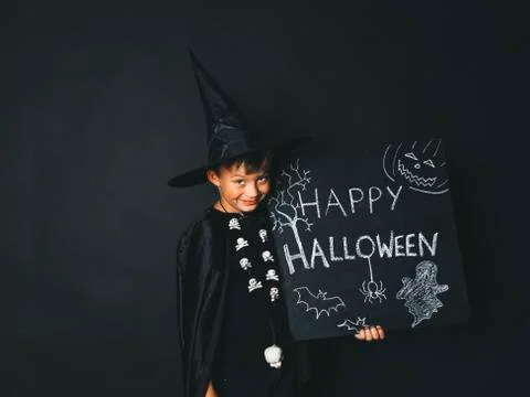 Young boy dressed as a magician is holding happy halloween chalkboard Stock Photos