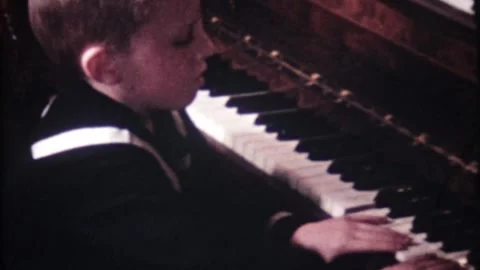 Young boy dressed in a sailor uniform plays the piano at home 7744 Stock-Footage 305082682