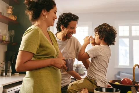 Young boy drinking his fruit juice in front of his parents Foto stock