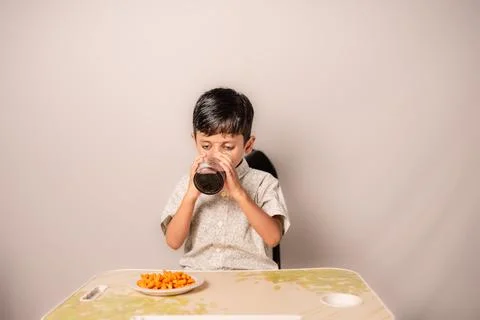 Young Boy Drinking Soda with Snacks at Home Table Stock-Fotos