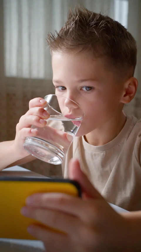 Young Boy Drinking Water and Using Smartphone Vertical. Stock Footage 320359888