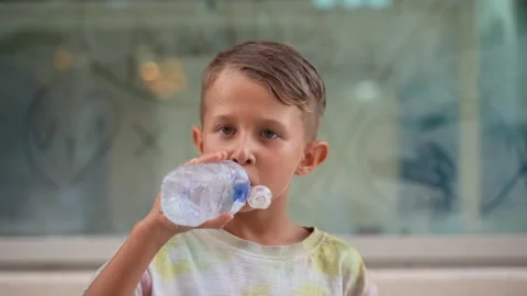 Young Boy Drinking Water from a Plastic Bottle Outdoors Stock-Footage 342662280