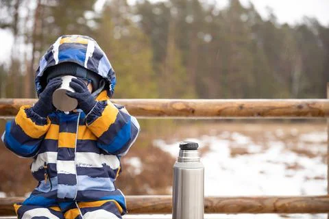Young boy drinks hot beverage from a cup in a cold raini day. Resting, taking Stock Photos