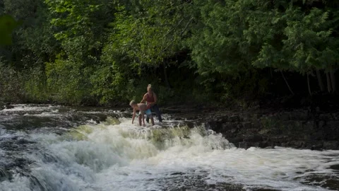 Young boy at dropoff edge of small scale waterfall Stock Footage 166631087