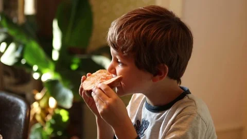 Young boy eating bread with marmalade Kid eating breakfast in the morning Stock Footage 70997951