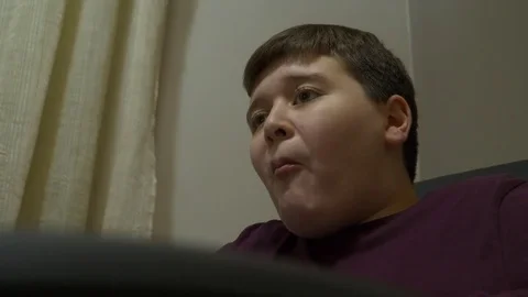 Young boy eating hamburger and watching TV Stock Footage 84266484