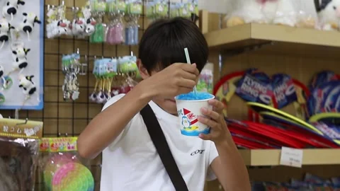 A young boy eating shaved ice in a small shop Stock Footage 246334724