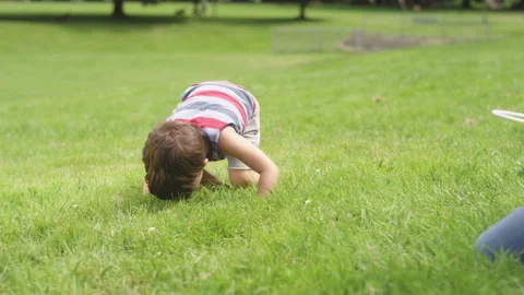 A young boy eats a bubble sitting on the grass at the park 스톡 동영상 143622990