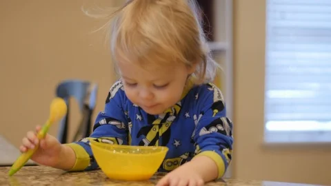 Young boy eats cereal at kitchen counter forgoes spoon and sticks face in bowl Stock Footage 86712239