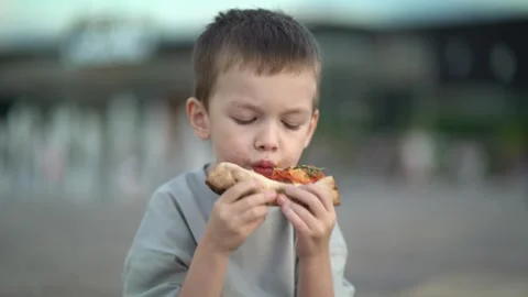 Young boy eats a messy snack with sauce on his face Vídeos de archivo 337678152