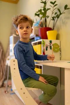 Young boy engaged in creative activity at colorful desk in a bright indoor space Stock Photos