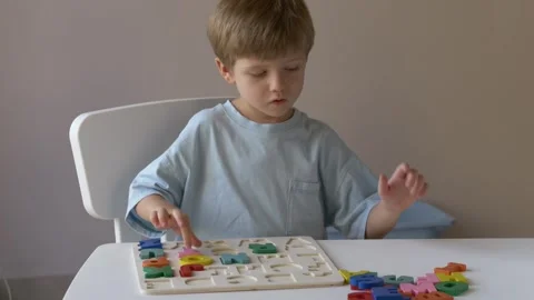 Young boy engaged in educational play, skillfully placing colorful letters into Stock Footage 318293779