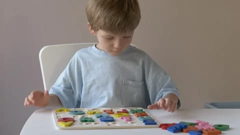 Young boy engaged in playful learning, skillfully placing colorful shapes into a Stock Footage 318294241