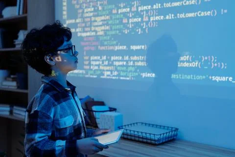 Young Boy Engaged in Programming with Projected Code 스톡 사진