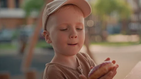 Young Boy Enjoying Donuts At Outdoor Table In Soft Daylight Close Up with donut Stock Footage 345968424