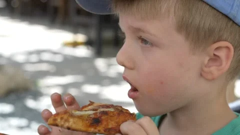 Young boy enjoying a slice of pepperoni pizza outdoors. Authentic family dining Stock Footage 335652725