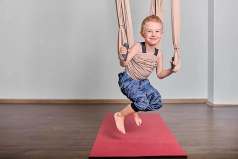Young boy enjoys aerial hammock exercise indoors Stock Photos