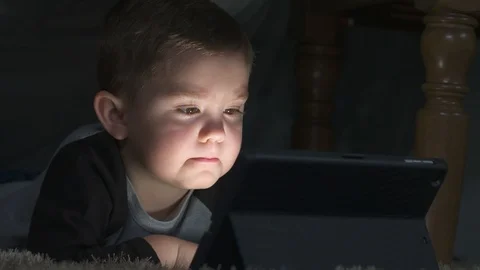 Young boy enjoys his tablet from the comfort of a blanket fort Stock Footage 85490281