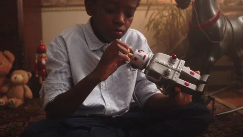 Young boy enjoys playing with a toy robot in a cozy playroom setting Stock Footage 319910728