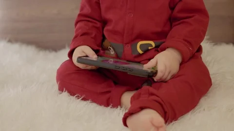 Young boy enjoys smartphone while surrounded by Christmas decorations and toys Stock Footage 314771840