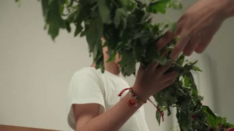 Young Boy Examining Fresh Green Herbs Bundle Indoors Видео 339069730
