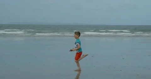 A young boy with excellent running style runs along a beach. Vídeos de archivo 79795818