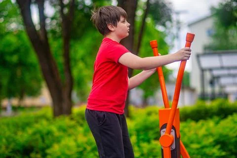 Young Boy Exercising on Outdoor Upper Body Fitness Machine in Park Stock-Fotos