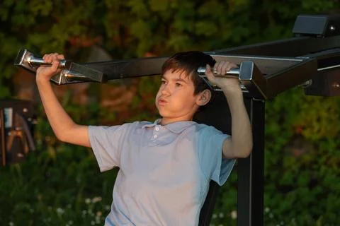 Young boy exercising with a weightlifting machine outdoors, focused express.. Foto stock