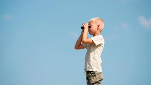 A young boy explorer looks through binoculars. Stock Photos