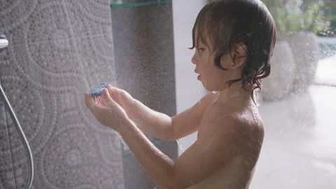 Young boy explores his collection of toy cars under a warm shower, delighting in Stock Footage 296715752