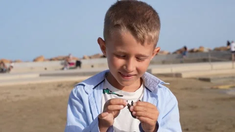 Young Boy Exploring a Beach and Holding a Small Object 스톡 동영상 333530152