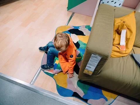 Young Boy Exploring IKEA s Textured Carpet and Klippan Sofa 写真素材