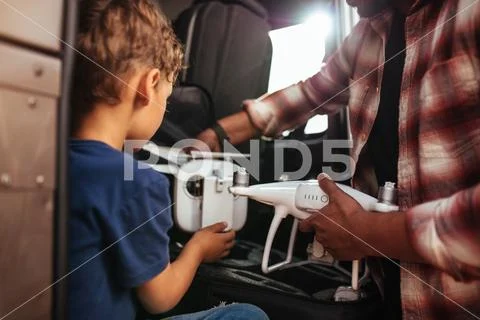Young boy with father holding small drone on road trip Stock Photos