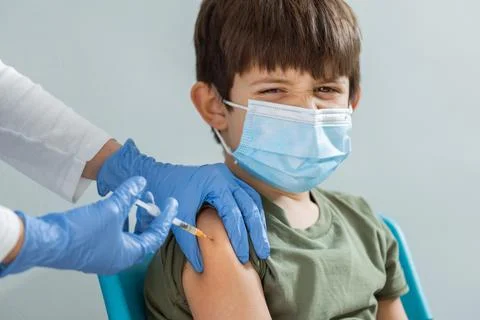 Young Boy feeling pain while getting a vaccine. Stock Photos